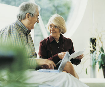 mature couple looking at laptop sitting on a couch